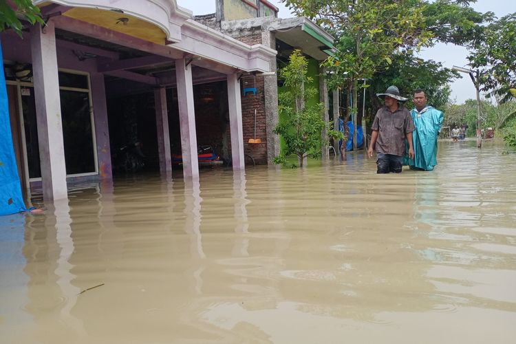 Warga saat melintasi genangan air akibat banjir luapan sungai tuntang yang merendam pemukiman warga di Desa Sumberejo Kecamatan Bonang Kabupaten Demak Jawa Tengah, Jumat (1/1/2021).
