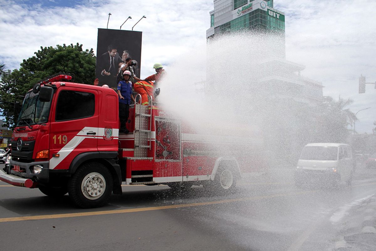 Petugas pemadam kebakaran menyemprotkan cairan disinfektan ke trotoar di Makassar, Sulawesi Selatan, Minggu (22/3/2020). Penyemprotan cairan disinfektan tersebut  guna mengurangi resiko penularan virus corona atau COVID-19 di sejumlah are publik mengingat telah ditemukannya dua kasus positif di Sulsel dan salah satu diantaranya meninggal dunia.