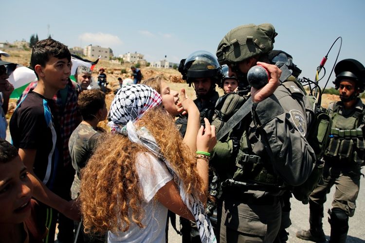 Remaja perempuan Palestina membentak tentara Israel saat aksi demonstrasi di Tepi Barat pada 12 Mei 2017 lalu. Warga Palestina termasuk perempuan dan anak-anak kerap terlihat ikut dalam aksi menentang negara Yahudi tersebut.