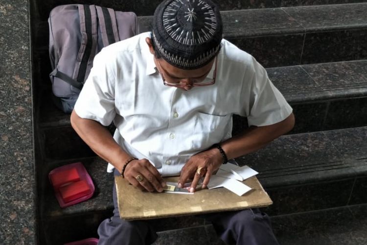 Tukang reparasi KTP, Udin (49), memperbaiki e-KTP yang rusak di area Masjid Fatahillah, Balai Kota DKI Jakarta, Rabu (6/2/2019).