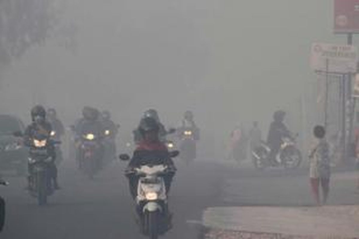 Warga tetap beraktivitas meski kabut asap menyelimuti Kota Pekanbaru, Riau, 20 Juni 2013. Kabut asap berasal dari kebakaran hutan di provinsi tersebut.