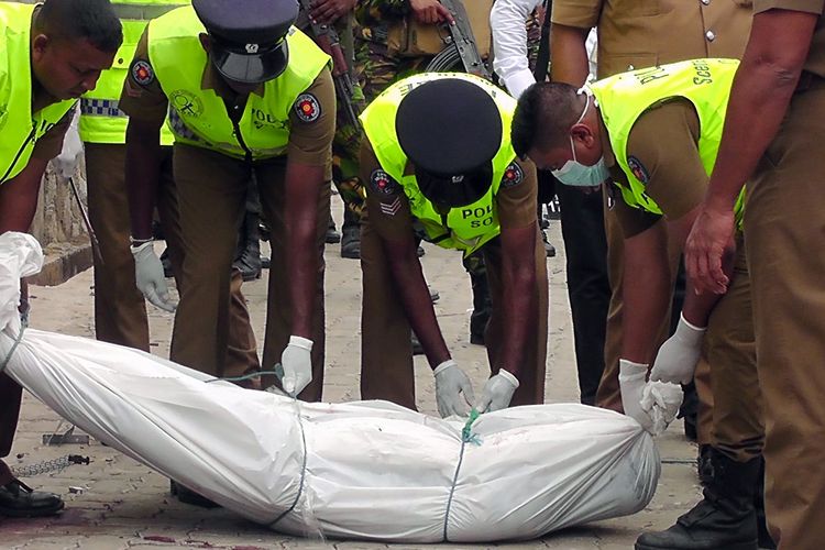 Polisi ketika mengangkat jenazah dari lokasi penyerbuan di Kalmunai, Sri Lanka, pada Jumat (26/4/2019). Penyerbuan itu dilakukan buntut ledakan bom yang terjadi pada MInggu Paskah yang menewaskan 253 orang (21/4/2019).