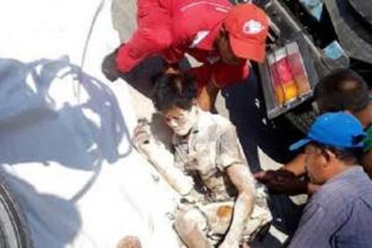 Petugas SPBU menolong seorang pria yang terluka setelah tersambar api yang memercik setelah sebuah truk menyenggol sebuah pompa bensin di Solo, Jawa Tengah.