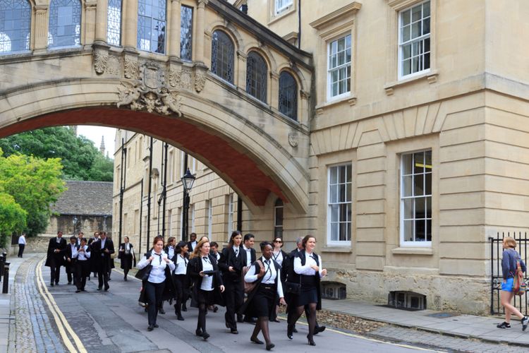 Para wisudawan University of Oxford tengah berjalan di Hertford College.
