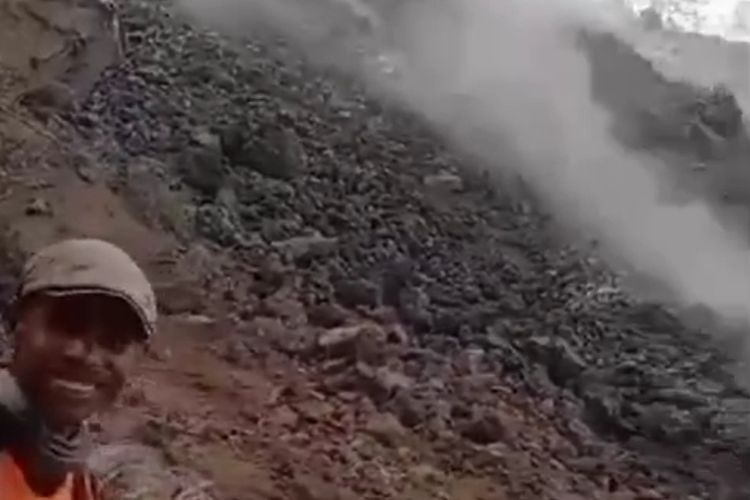 Tangkapan layar seorang pria sedang menonton lava yang sedang mengalir dari puncak Gunung Ile Lewotolok dari jarak dekat