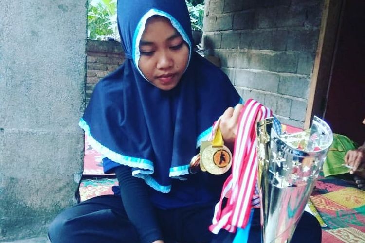 Yuliana (17), atlet Indonesia yang menjadi juara dalam Kejuaraan Dunia Pencak Silat Junior di Thailand pada April 2018, bersama medali dan pialanya.