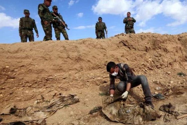 Seorang pria Irak memeriksa tulang-belulang anggota kelompok minoritas Yazidi yang dibunuh oleh kelompok militan Negara Islam (IS), setelah pasukan Kurdi menemukan sebuah kuburan massal di dekat Desa Sinuni, di barat laut Sinjar.