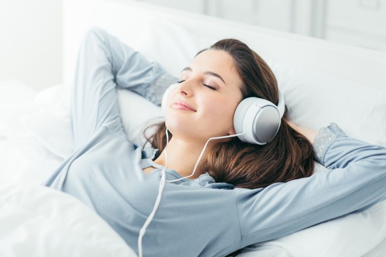 Ilustrasi seorang wnaita mendengarkan musik sembari tidur