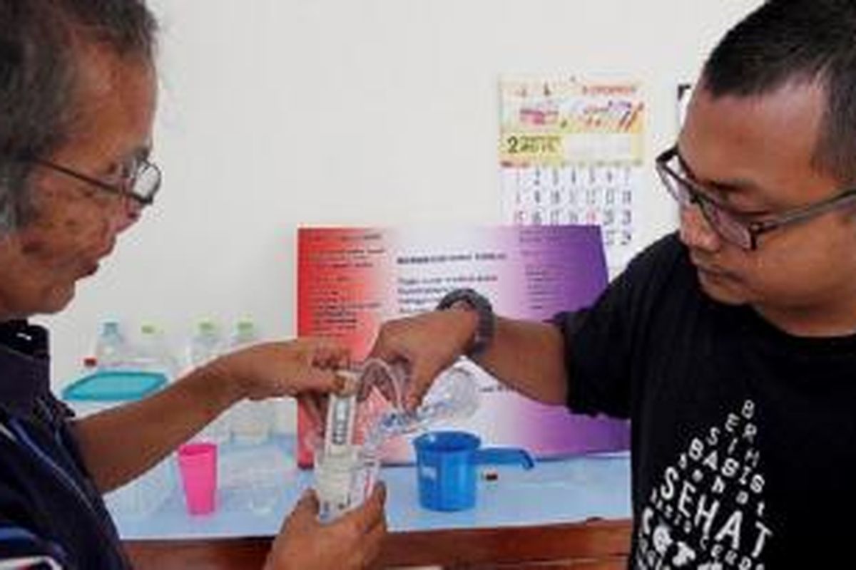 Romo Kirjito (kiri) dan asistennya, Rakatiyaji (kanan), mengukur PH air hujan di laboratoriumnya, di Muntilan, Kabupaten Magelang, Jawa Tengah, Sabtu (28/2). Kirjito tengah meneliti air hujan yang diionisasi sebagai sumber air minum.
