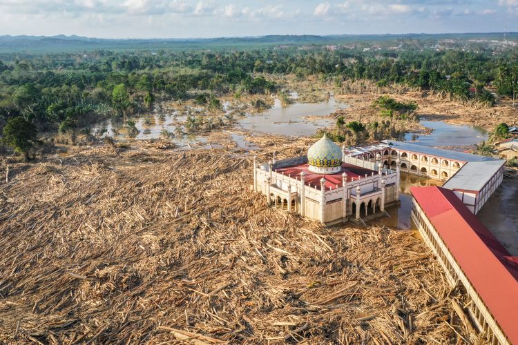 Foto udara menampilkan tumpukan kayu-kayu memenuhi area Pondok Pesantren Darul Mukhlishin pascabanjir bandang di  Desa Tanjung Karang, Karang Baru, Kabupaten Aceh Tamiang, Aceh, Jumat (5/12/2025). Usai sepekan setelah bencana banjir bandang, akses menuju Desa Tanjung Karang masih terhambat akibat banyaknya tumpukan pohon dan lumpur tebal dari Sungai Tamiang sehingga bantuan sulit masuk ke wilayah tersebut. 