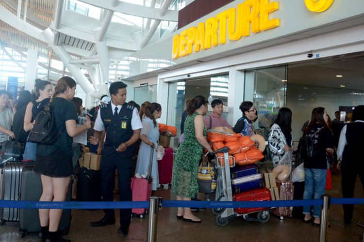 Sejumlah penumpang menunggu jadwal penerbangan di Bandara Ngurah Rai, Bali, Jumat (29/6/2018).  