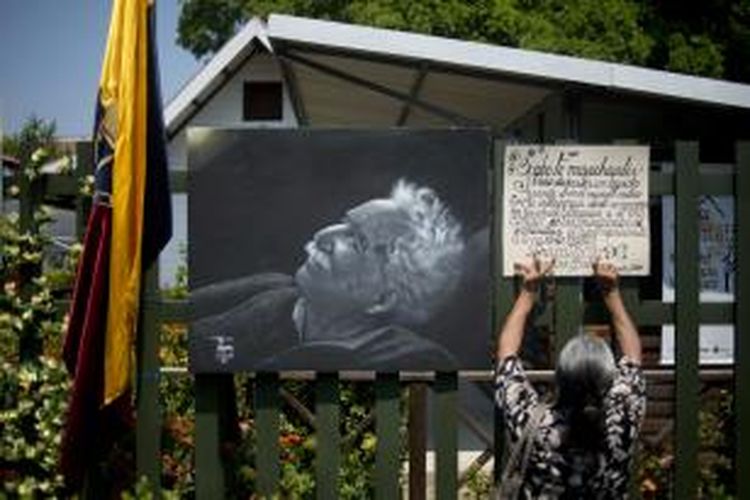 Seorang perempuan, Jumat (18/4/2014), menempelkan pengumuman di samping gambar wajah Gabriel Garcia Marquez, penulis dan penerima Nobel Sastra 1982, yang meninggal pada Kamis (17/4/2014) dalam usia 87 tahun.