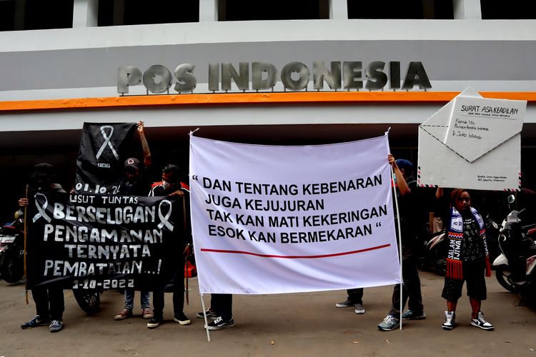 Ratusan suporter Arema FC, membentangkan spanduk saat menggelar aksi kirim Surat dari Aremania untuk Presiden Jokowi Menuntut Usut Tuntas Tragedi Kanjuruhan di Kantor Pos Kota Malang, Kamis (17/11/2022) siang.