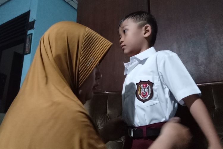 Fanny Ampiyani (42), ibu dua anak asal Kabupaten Cianjur, Jawa Barat ini tengah menyeragami anaknya yang bersiap ke sekolah di hari pertama tahun ajaran baru, Senin (17/7/2023).
