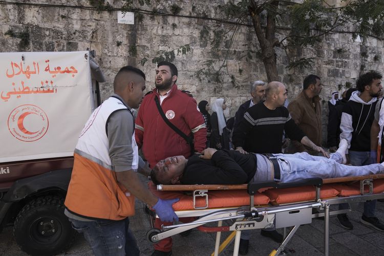 Tim medis mengevakuasi seorang pria Palestina yang terluka dalam bentrok di masjid Al Aqsa antara pedemo Palestina dan pasukan Israel di Yerusalem, Jumat (15/4/2022).