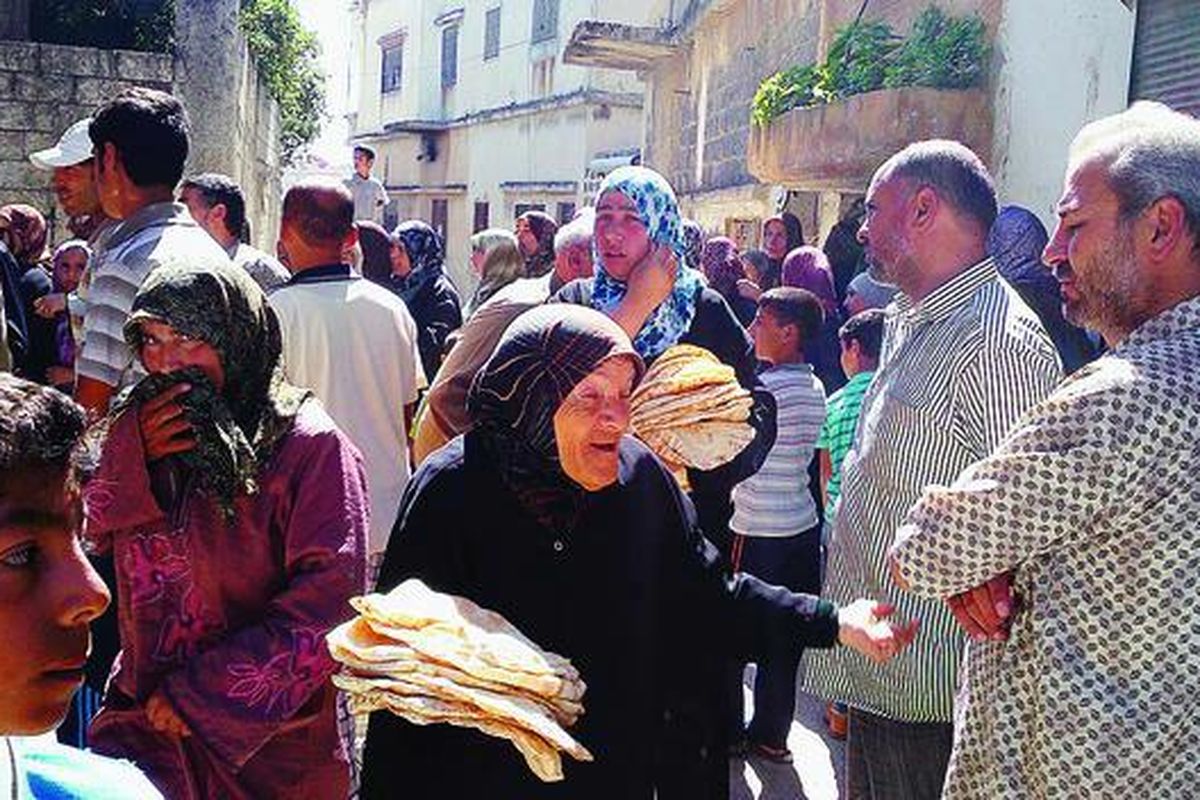 Warga Suriah antre untuk mendapatkan makanan di kota Houla, lokasi terjadinya pembantaian 108 warga sipil pada bulan lalu, yang terletak di Provinsi Homs, Sabtu (9/6). Lembaga Pemantau Hak Asasi Suriah mengatakan, terjadi pembunuhan massal lagi oleh kelompok bersenjata yang mendukung rezim Presiden Bashar al-Assad di  Daraa, yang menyebabkan puluhan warga sipil tewas.