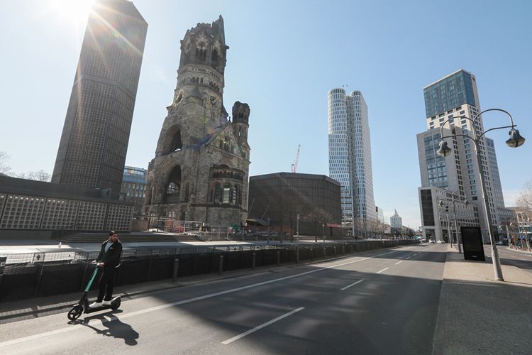 Seorang pria mengendarai skuter elektrik miliknya di sebuah jalan kosong dekat Kaiser Wilhelm Memorial Church di Berlin, saat penyebaran virus corona (COVID-19) masih terus berlanjut di Jerman, Rabu (25/3/2020).