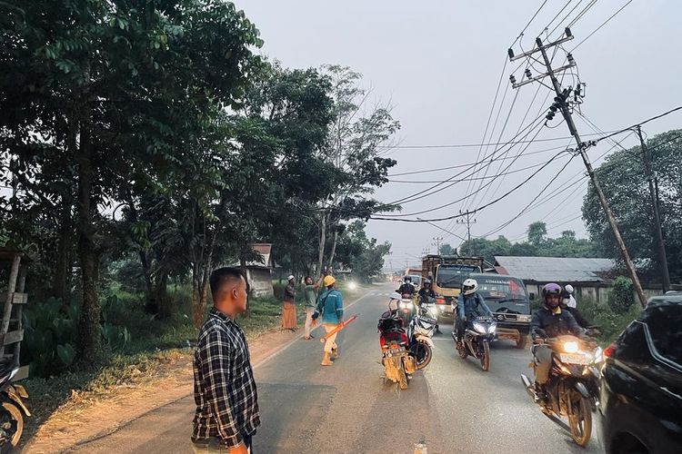 Sebuah tiang listrik di Jalan Trans Kalimantan, Kecamatan Ambawang, Kubu Raya, Kalimantan Barat, miring dan menyebabkan kabelnya menjuntai. Kondisi ini membuat kendaraan truk tidak bisa lewat dan bikin macet. Gambar diambil pada Selasa (15/8/2023) petang.