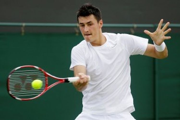 Petenis Australia, Bernard Tomic, memukul bola ke arah Sam Querrey dari Amerika Serikat, saat saling berhadapan di babak pertama Wimbledon, Selasa (25/6/2013).