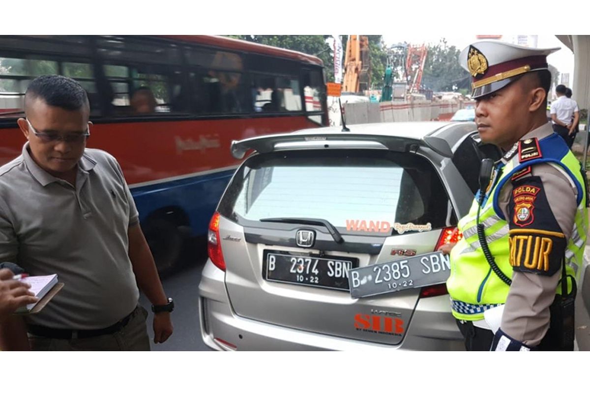 Pengemudi Honda Jazz bernama Wanda ditilang polisi karena kedapatan memiliki pelat ganda untuk menghindari aturan pembatasan kendaraan berdasarkan nomor pelat ganjil dan genap di Jalan Gatot Subroto, simpang Pancoran, Jakarta Selatan, Rabu (1/8/2018). Petugas kepolisian mulai memberlakukan penindakan berupa tilang terhadap pengendara mobil yang melanggar di kawasan perluasan sistem ganjil-genap.