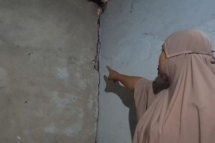 Agustina, warga Dusun Kaliangga, Desa Batang Merangin Kabupaten Kerinci sedang menunjukkan dinding kamarnya yang mengalami keretakan usai aktivitas peledakan dinamit dalam terowongan PLTA