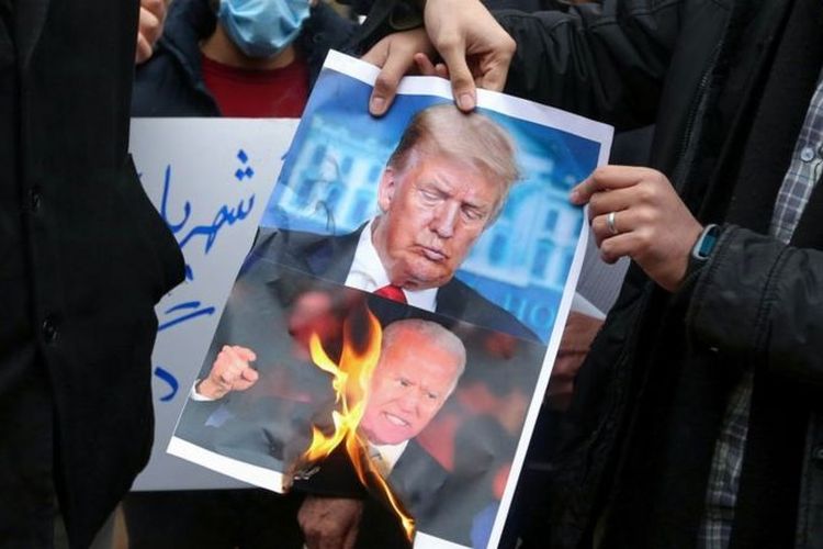 Warga Iran membakar poster bergambar Trump dan Biden dalam demo di Teheran, akhir November lalu.