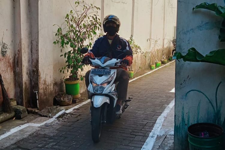 Seorang driver Jeggboy & Girl mengantar pesanan konsumen di sebuah gang Kota Salatiga.