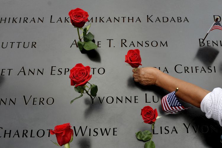 Dalam file foto 11 September 2014 ini, seorang wanita meletakkan bunga dengan nama yang tertulis di sepanjang tepi North Pool selama peringatan peringatan 13 tahun serangan teror 11 September 2001 di World Trade Center di New York.