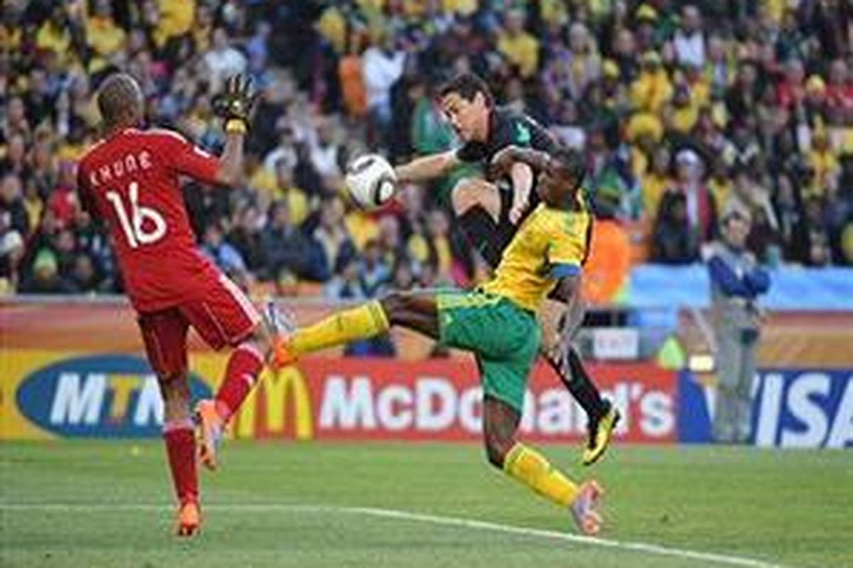 Striker Meksiko Guillermo Franco (baju hitam) melepaskan bola ke gawang Afrika Selatan yang dikawal kiper Itumeleng Khune pada pertandingan pembuka Piala Dunia 2010 di Stadion Soccer City, Jumat (11/6/2010).