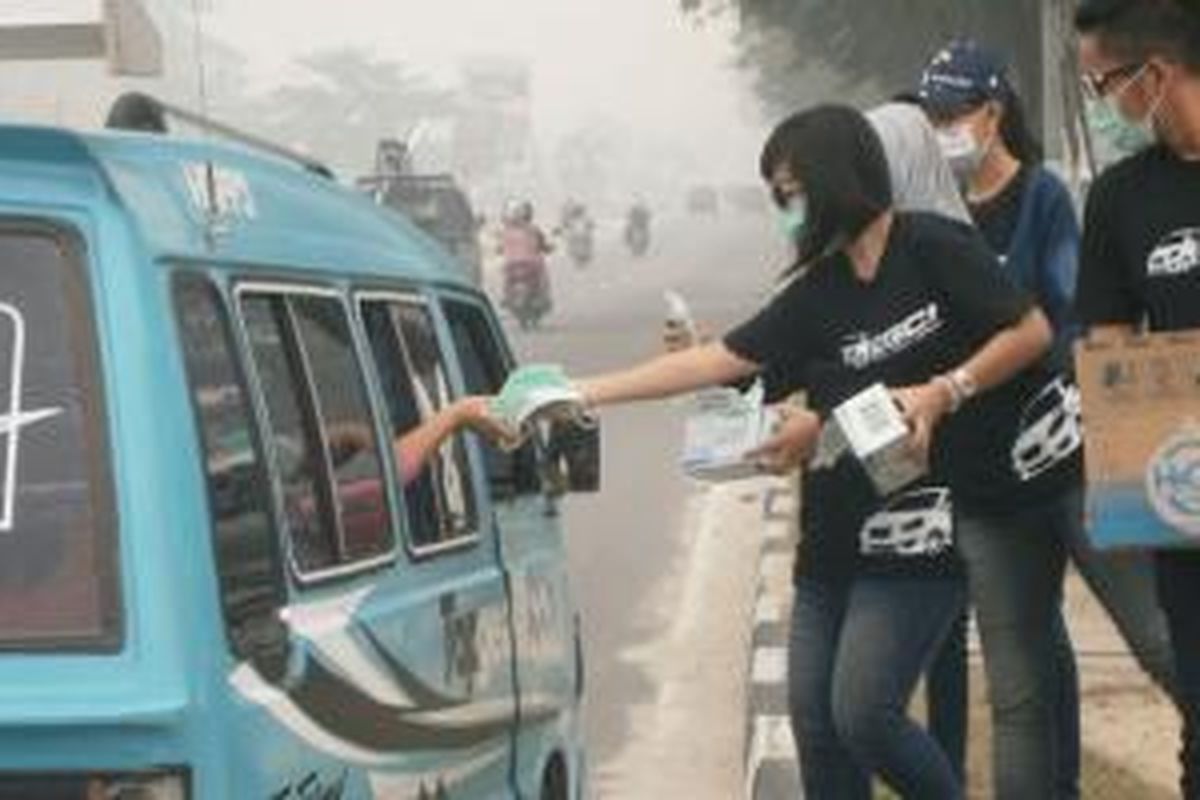 Para anggota Datsun Go  Panca Club Indonesia (DGCI) sedang membagikan masker dan air mineral di Pekanbaru, terpicu oleh kabut asap yang tak kunjung bisa ditangani.