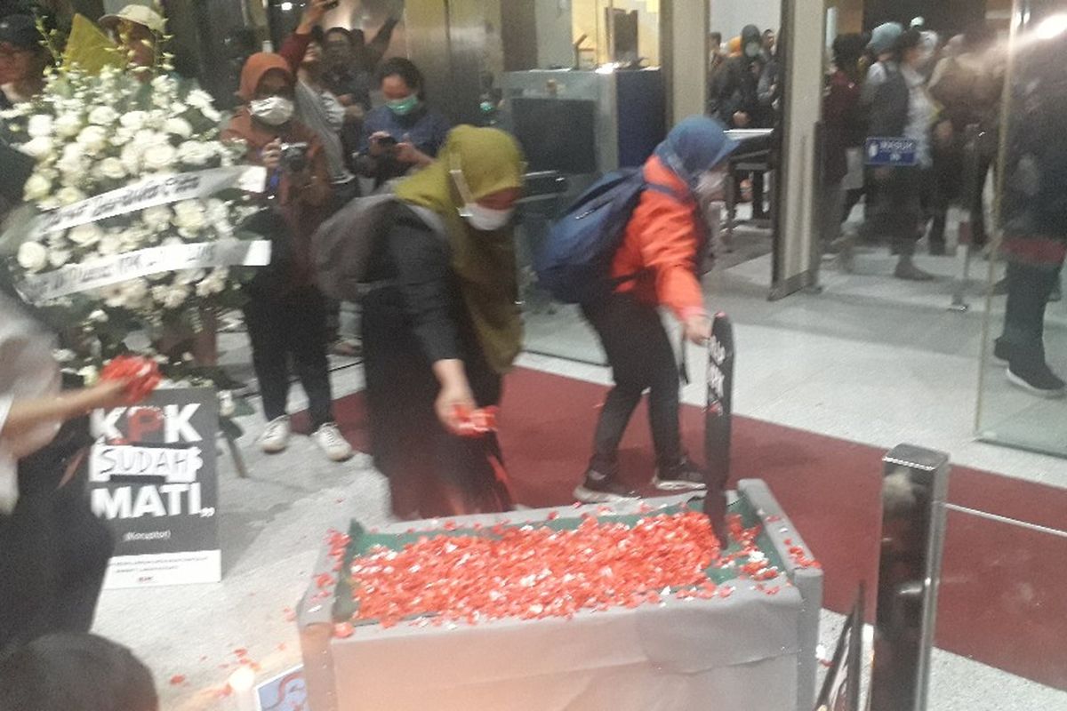 Peserta aksi menaburkan bunga di atas replika pusara makam yang ditaruh di pintu masuk Gedung Merah Putih KPK, Selasa (17/9/2019).