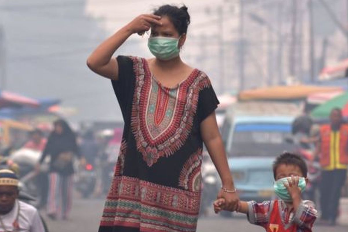 Seorang ibu dan anaknya mengenakan masker medis saat asap kebakaran hutan dan lahan (Karhutla) menyelimuti Kota Pekanbaru, Riau, Selasa (10/9/2019). 