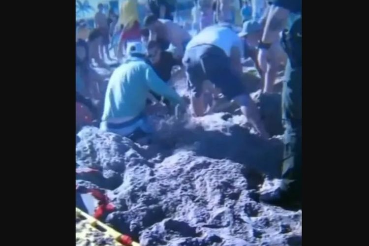 Para pengunjung pantai dan tim penyelamat menggali dengan panik untuk menyelamatkan gadis setelah pasir runtuh menimpanya.