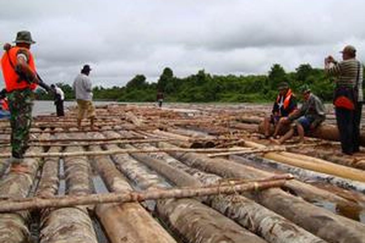 JAGA - Aparat TNI dari Yonif 643 dengan senjata laras panjang SS1 menjaga kayu log di Sungai Radak, Minggu (7/12).