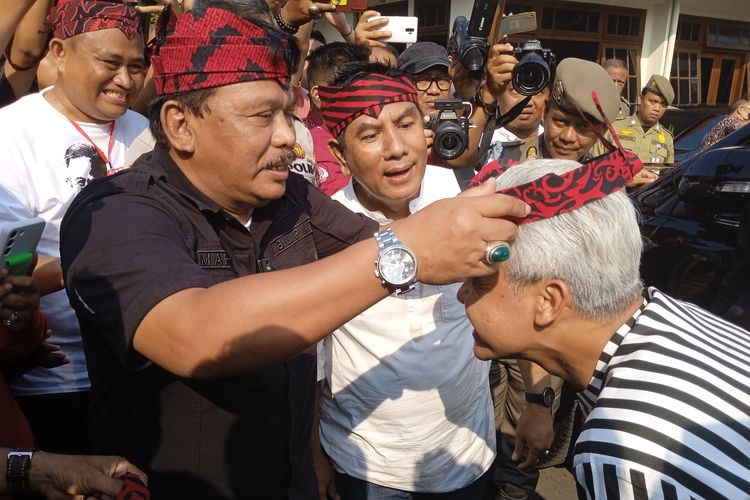 Bupati Nganjuk Marhaen Djumadi saat memakaikan udeng anjuk ladang ke Ganjar Pranowo, Jumat (23/6/2023)