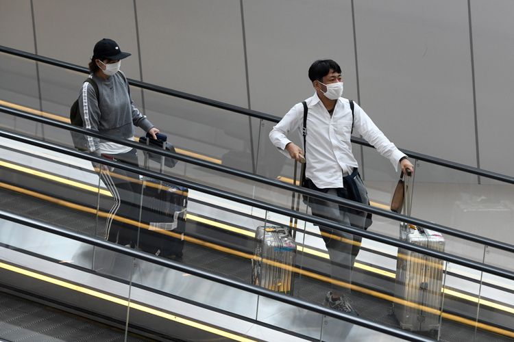 Penumpang mengenakan masker untuk melindungi diri dari penyebaran Covid-19 coronavirus, saat menunggu penerbangan di Bandara Internasional Changi, di Singapura, 27 Februari 2020