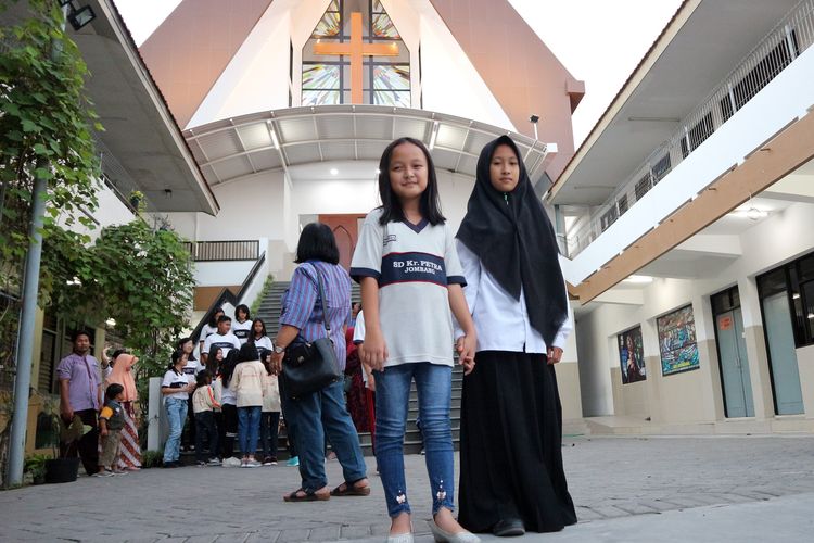 Siswi MI Islamiyah dan SD Kristen Petra Jombang, saat berpose bersama di depan pintu tangga menuju Gereja Kristen Indonesia (GKI), menjelang acara buka puasa bersama di SD Kristen Petra Jombang, (27/5/2019) petang.                      