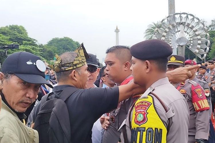 Massa demo pro-kontra cekcok dan ditahan oleh polisi di Patung Kuda, Gambir, Jakarta Pusat, Rabu (27/3/2024).