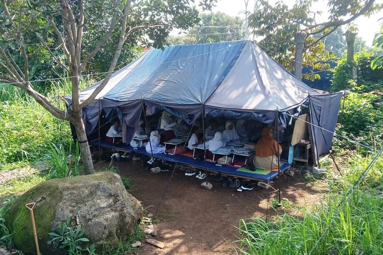 Salah satu lokasi tenda yang dijadikan tempat belajar murid SDN Cugenang, Kabupaten Cianjur, Jawa Barat, Senin (20/11/2023). Mereka terpaksa menjalani KBM dengan kondisi tak nyaman karena bangunan sekolah mereka yang rusak akibat gempa tahun lalu tak kunjung diperbaiki.