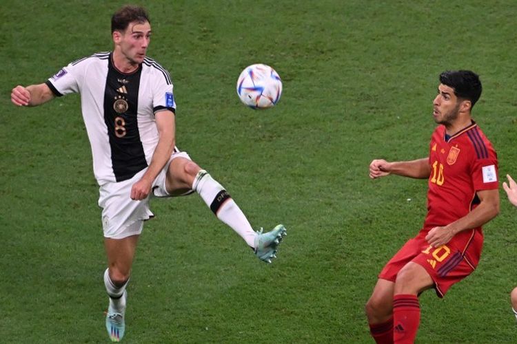 Leon Goretzka (8) berduel dengan Marco Asensio (10) dalam laga Grup E Piala Dunia 2022 antara Spanyol vs Jerman di Stadion Al Bayt, Al Khor, Qatar, 27 November 2022. (Photo by Kirill KUDRYAVTSEV / AFP)