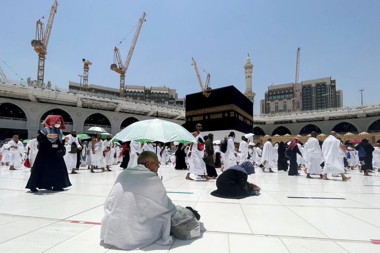Seorang jamaah haji duduk sambil menaungi diri dengan payung di Masjidil Haram dalam Haji pertama setelah pemerintah Kerajaan Arab Saudi membuka kembali kegiatan Haji untuk warganegara asing yang ditutup akibat pandemi COVID-19 selama dua tahun di Mekah, Arab Saudi, Jumat (1/7/2022). (ANTARA FOTO/REUTERS/Mohammed Salem/wsj/NBL).