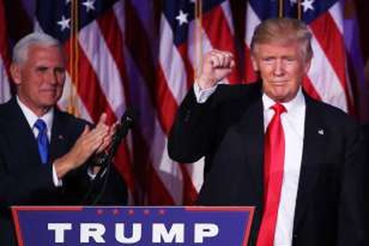 Donald Trump mengepalkan tangannya saat memastikan kemenangan dalam pemilihan presiden AS tahun ini. Di belakangnya terlihat pasagannya, Mike Pence.