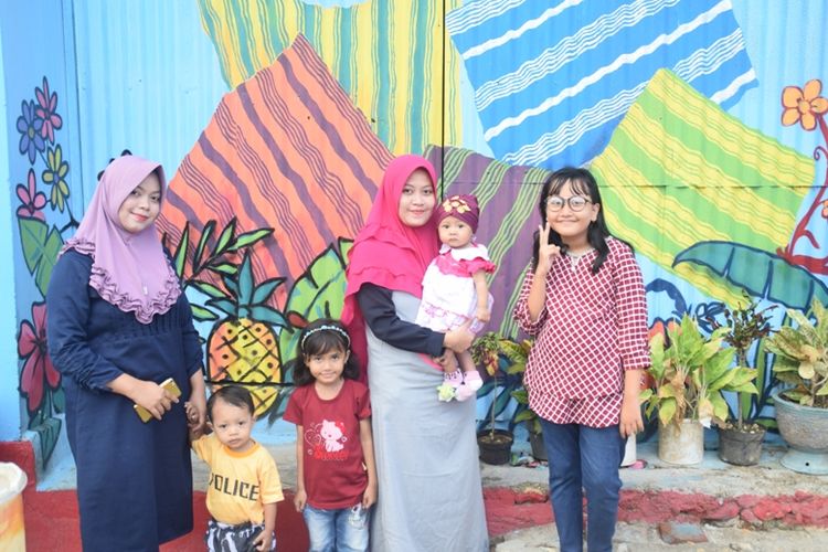 Para pengunjung berfoto dengan latar belakang Kampung Tenun Warna Warni di Kampung Sulaa, Baubau, Sulawesi Tenggara.