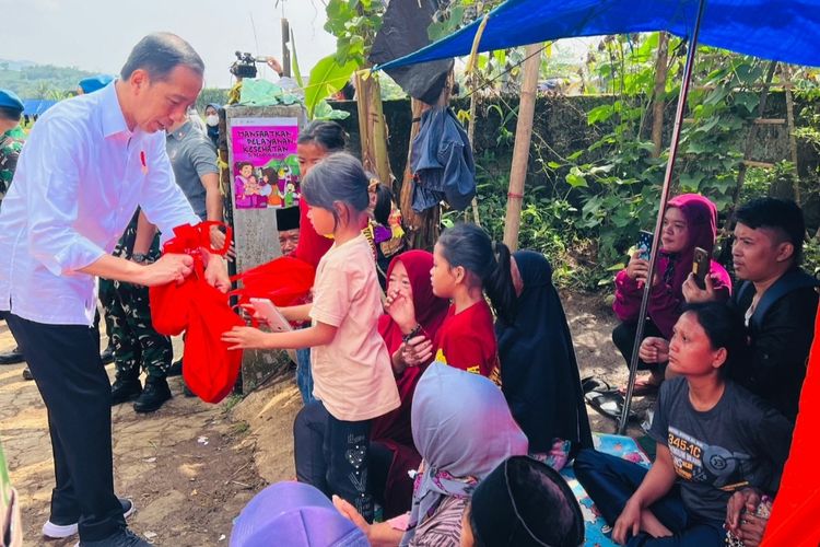 Presiden Joko Widodo menyerahkan bantuan saat meninjau Posko Bantuan Peduli Cianjur di Desa Cijedil, Kecamatan Cugenang, Cianjur, Senin (5/12/2022).