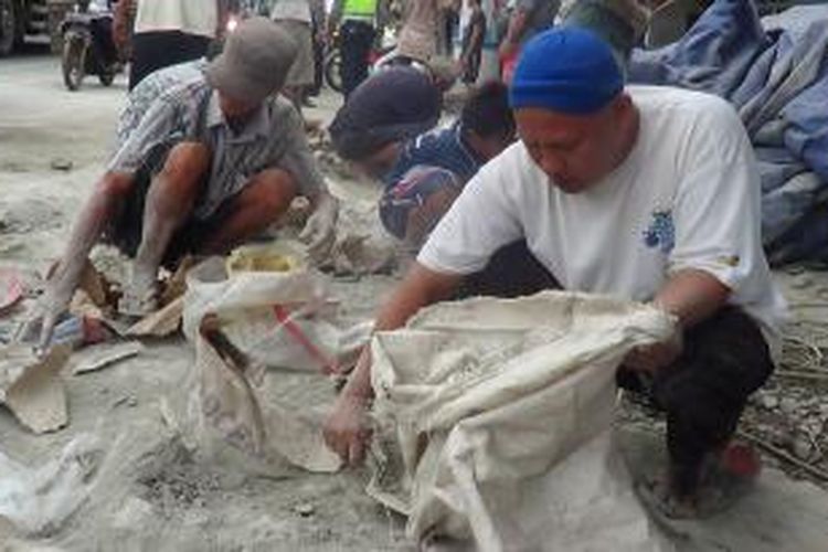 Warga mengambil ceceran semen yang tumpah di jalur pantura Sumur Panggang, Kota Tegal, Jawa Tengah, Selasa (31/12/2013).