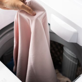 Ilustrasi mencuci pakaian menggunakan mesin cuci.