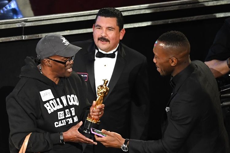 Aktor Mahershala Ali (kanan) mengizinkan seorang turis memegang Piala Oscar-nya pada perhelatan Academy Awards di Dolby Theater, Hollywood, California, Minggu (26/2/2017).