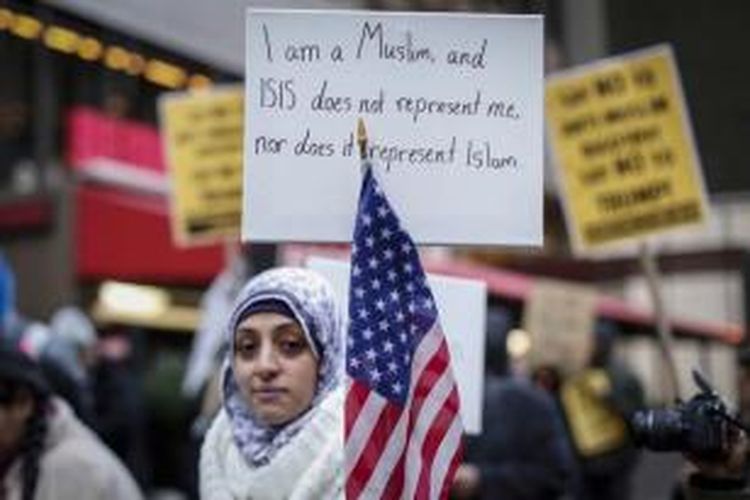 Seorang wanita muslim membawa poster saat ikut berunjuk rasa mengecam Donald Trump di New York, 20 Desember 2015. Capres AS Donald Trump dari Partai Republik menyerukan semua pencegahan semua muslim masuk ke AS.