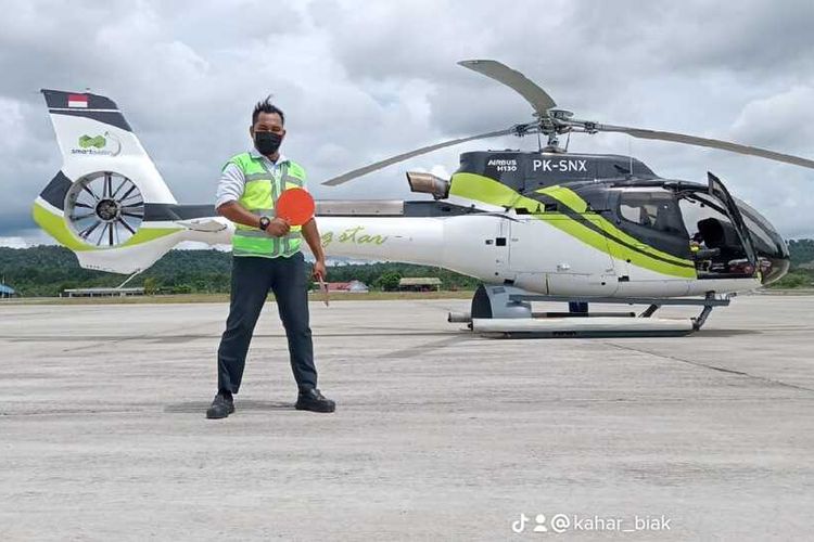 Petugas Ramp Handling Bandara Frans Kasiepo Biak Numfor, Kaharuddin (36), saat berfoto dibalik helikopter yang parkir di Bandara Frans Kasiepo, Senin (29/11/2023).