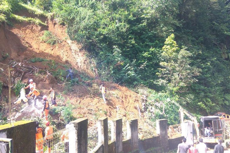 Petugas gabung dan satu unit ekskavator membersihkan material longsor yang menutup jalan di Desa Sukamaju Kecamatan Cihaurbeuti Kabupaten Ciamis Jawa Barat, Senin (12/9/2022).